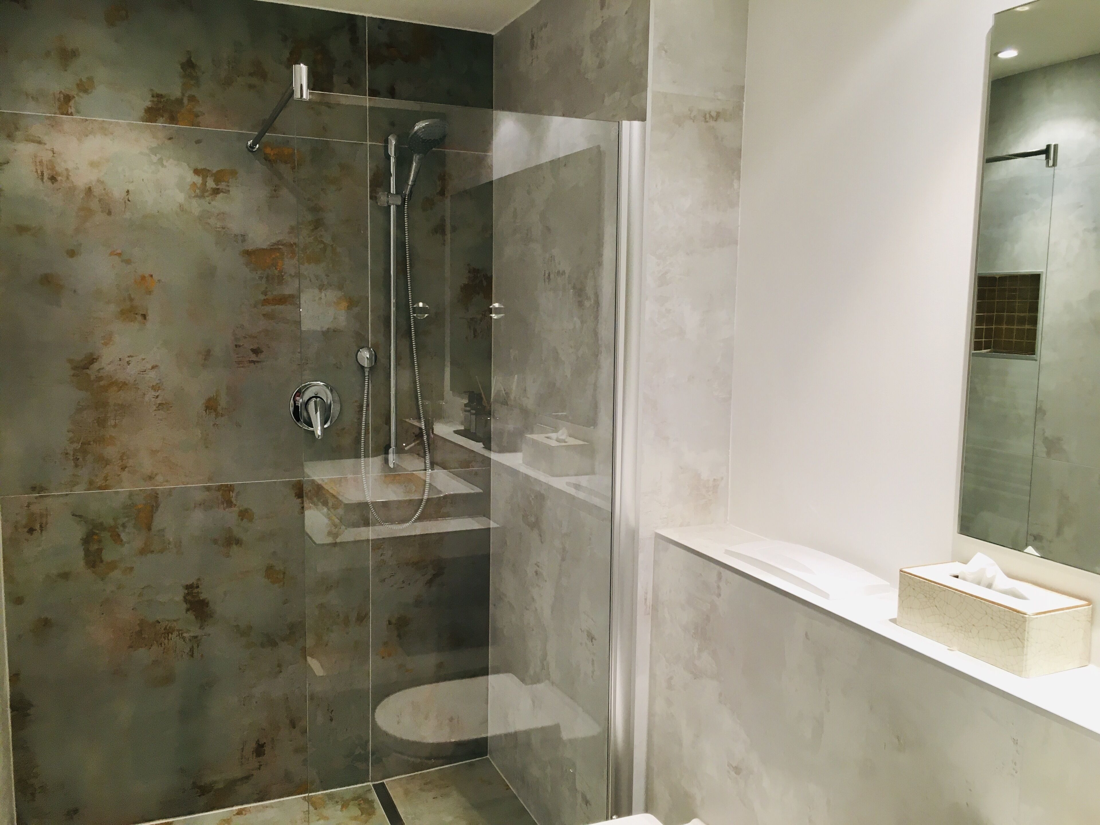 A modern bathroom with a glass-enclosed shower, a white sink, and a mirror above the sink.