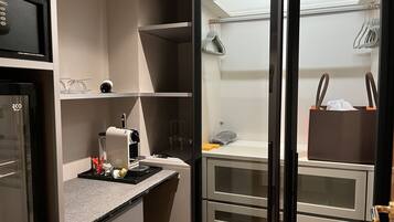 A compact kitchenette with a coffee machine, a small sink, and a countertop.