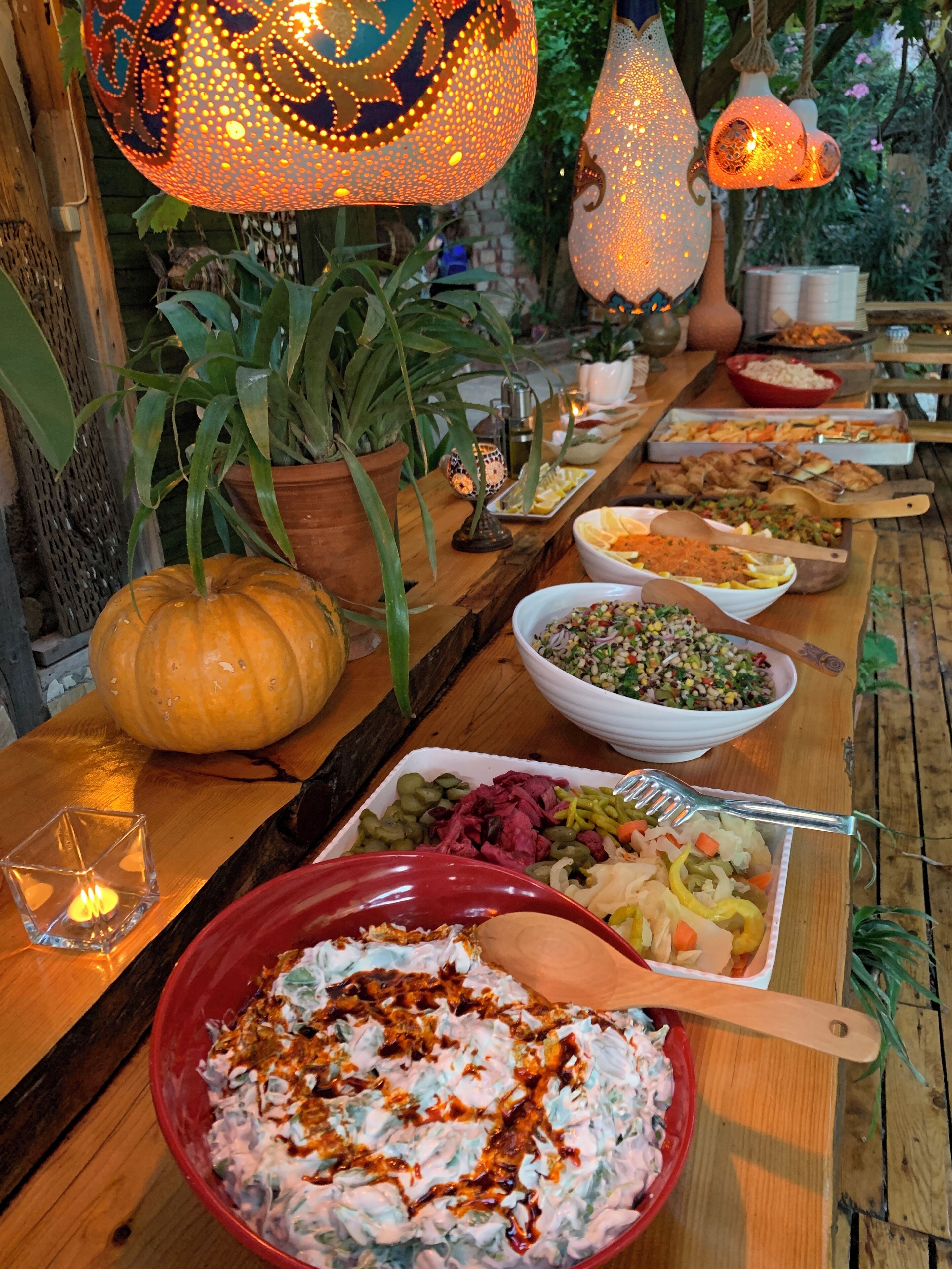 A wooden table with various dishes, a potted plant, and decorative hanging lights.