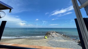 Blick auf einen Strand vom Inneren eines Fahrzeugs aus, mit blauem Himmel und ruhiger See.