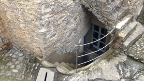 Ein Steinhaus mit einem schmalen Eingang und einer Metalltreppe, die nach oben führt.