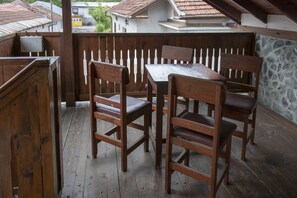 A wooden deck with a table and four chairs, surrounded by a wooden fence and a stone wall. - Medic Hotel (Sofia)