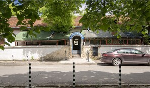 A building with a stone facade, a tiled roof, and a blue entrance archway. - Medic Hotel (Sofia)