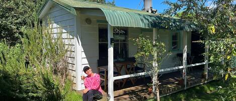A quaint cottage with a green roof, a porch, and a small garden area.