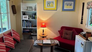 Un salon confortable avec un canapé, une petite table avec une lampe, une bibliothèque et un réfrigérateur.