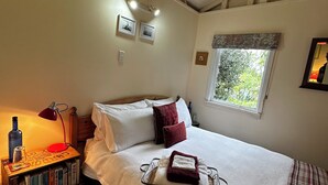 Une chambre à coucher avec un lit, une table de chevet, une lampe et une fenêtre donnant sur un paysage verdoyant.
