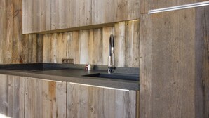 A kitchen with a wooden backsplash and a modern faucet. - Beautifully appointed mountain studio, close to the village of Megève, sleeps 4. (Megève)