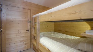A bunk bed room with wooden walls and a door. - Beautifully appointed mountain studio, close to the village of Megève, sleeps 4. (Megève)