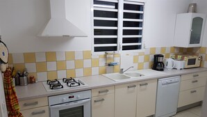 A kitchen with a gas stove, oven, sink, and a microwave. - Renting a furnished tourist apartment with sea view (ANSES-D ARLET)