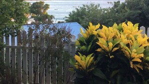 A coastal view with a wooden fence, potted plants, and a distant shoreline. - Renting a furnished tourist apartment with sea view (ANSES-D ARLET)