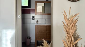 Een moderne badkamer met een houten wastafelmeubel, een spiegel en een wandklok.