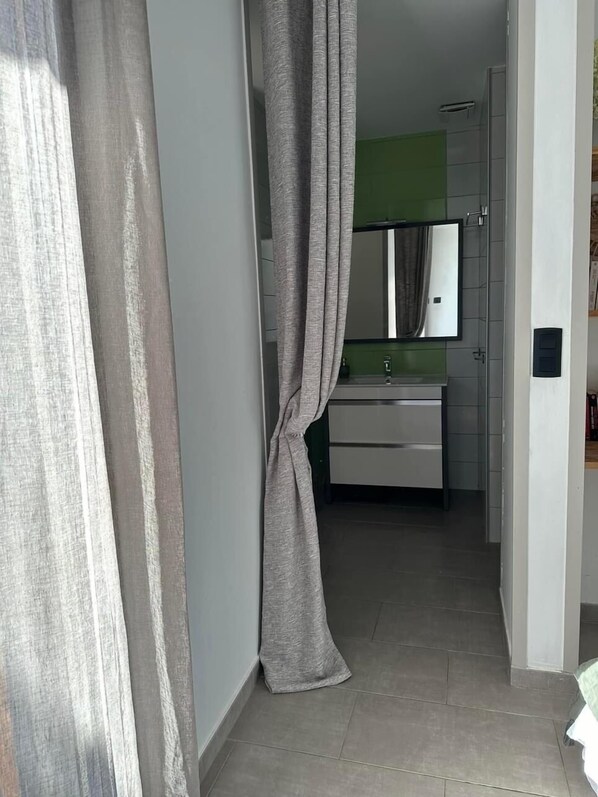 A bathroom with a white sink, a mirror, and a green wall.