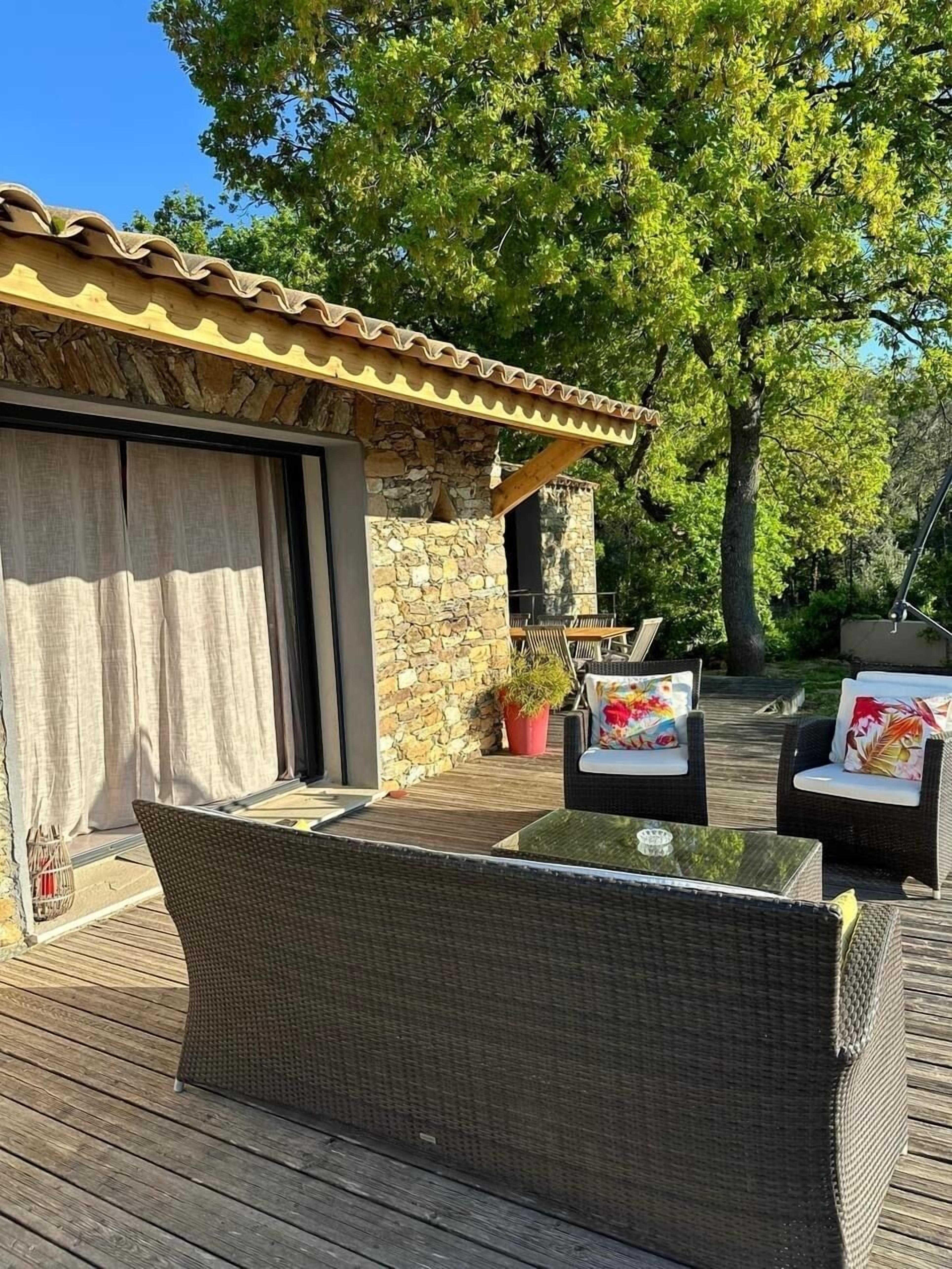 A wooden deck with wicker furniture and a stone wall.