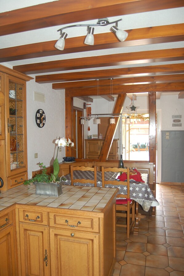 A kitchen with wooden cabinets, a tiled backsplash, and a dining area with a table and chairs.