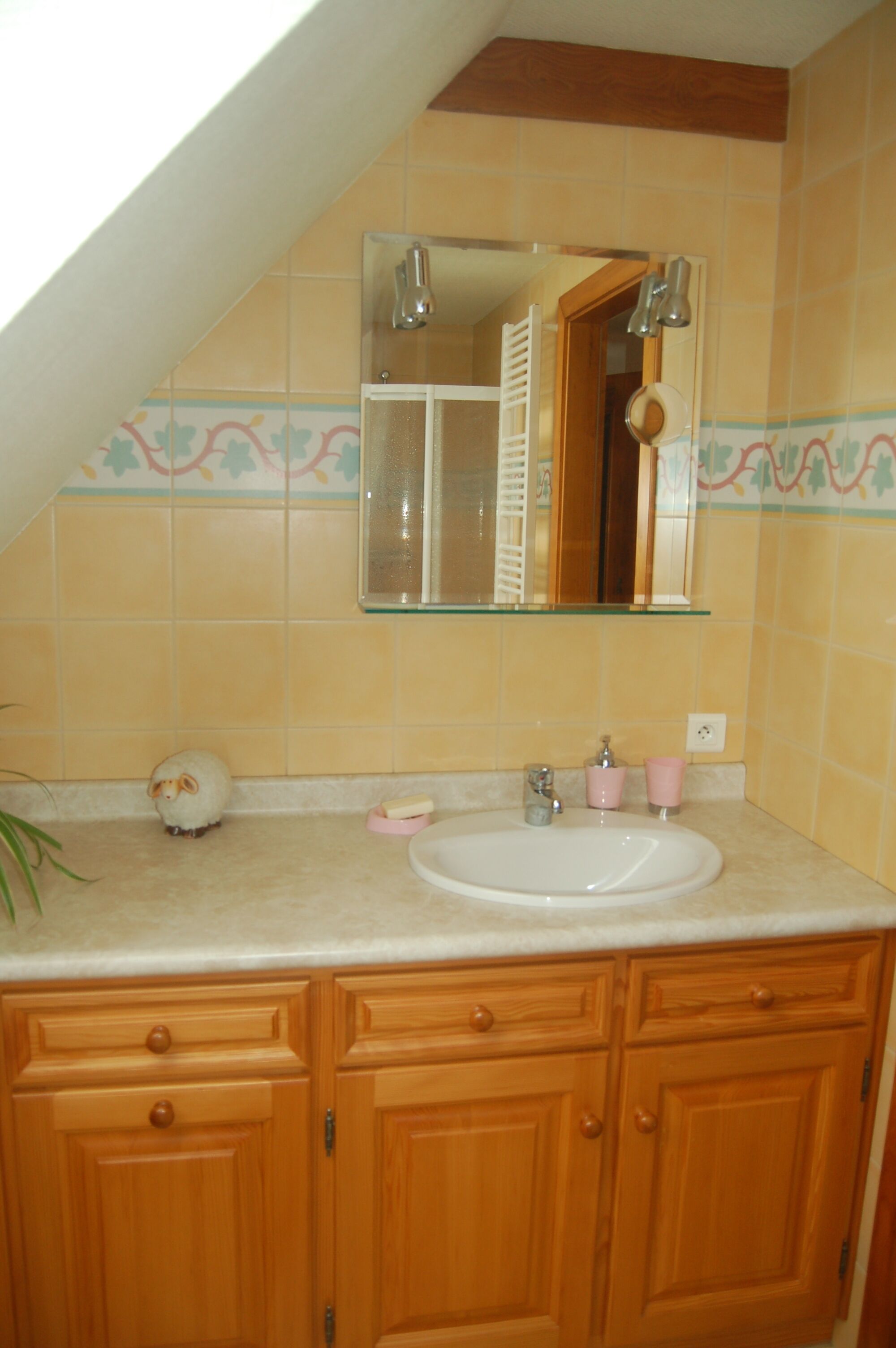 A bathroom with a sink, mirror, and wooden cabinets.
