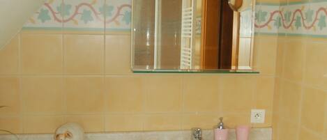 A bathroom with a sink, mirror, and wooden cabinets.