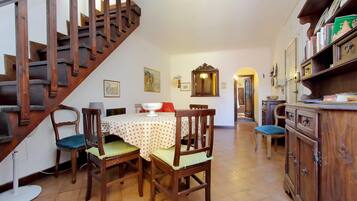 A dining area with a wooden staircase, a dining table with chairs, and a cabinet with dishes.
