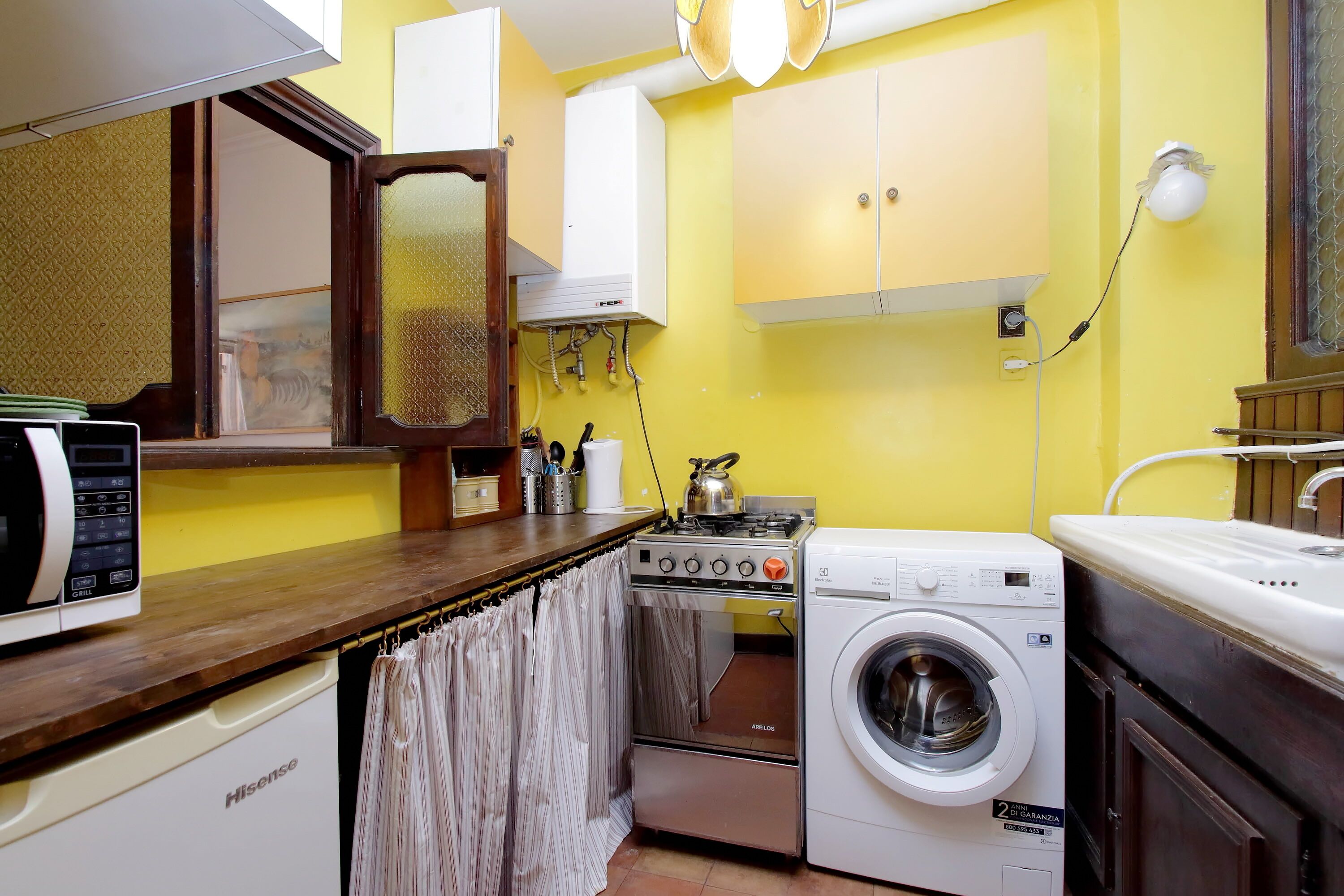 Una cocina compacta con microondas, estufa y lavadora.