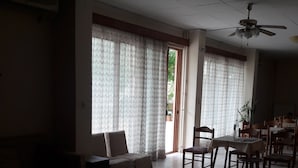 A spacious living area with a sofa, a dining table with chairs, and a ceiling fan. - Nestor (Zacharo)