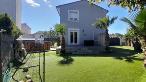 A modern two-story house with a well-maintained lawn, a small patio, and a few palm trees. - Villa close to the beach (Aimargues)