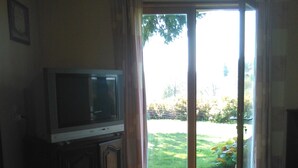 A living room with a television on a cabinet, a sofa, and a dining table.