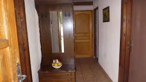 A wooden dresser with drawers and a mirror, a small fruit bowl on top, and a wooden door with a mirror in the background.