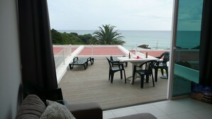 A balcony with a table and chairs, overlooking the sea.