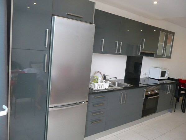 A modern kitchen with grey cabinets, stainless steel appliances, and a black countertop. - QUIET BEACH 5 METRES (ALBUFEIRA)