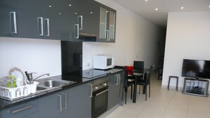 A modern kitchen with a built-in oven, microwave, and a dining area with a TV and a red bowl.