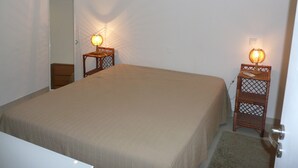A bedroom with a large bed, two nightstands with lamps, a mirror, and a door.