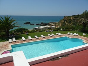 A pool with white lounge chairs and a view of the ocean. - QUIET BEACH 5 METRES (ALBUFEIRA)