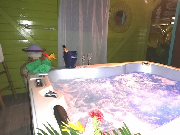 A hot tub with a decorative flower arrangement and a bottle of champagne.