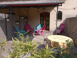 Un patio techado con sillas coloridas, una mesa y plantas en macetas.