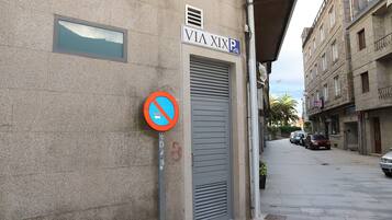 A street with a no parking sign, a building with a 'VIA XIX' sign, and parked cars.
