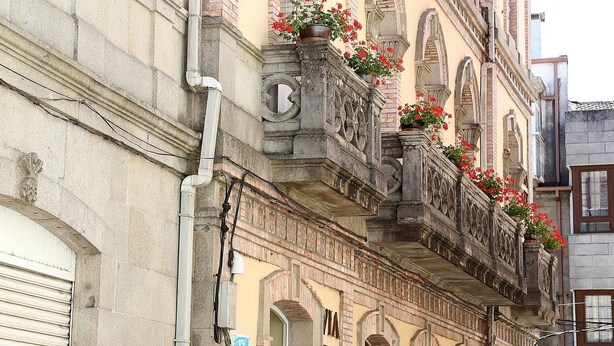 Un edificio histórico con ventanas de arco y un balcón con macetas de flores.