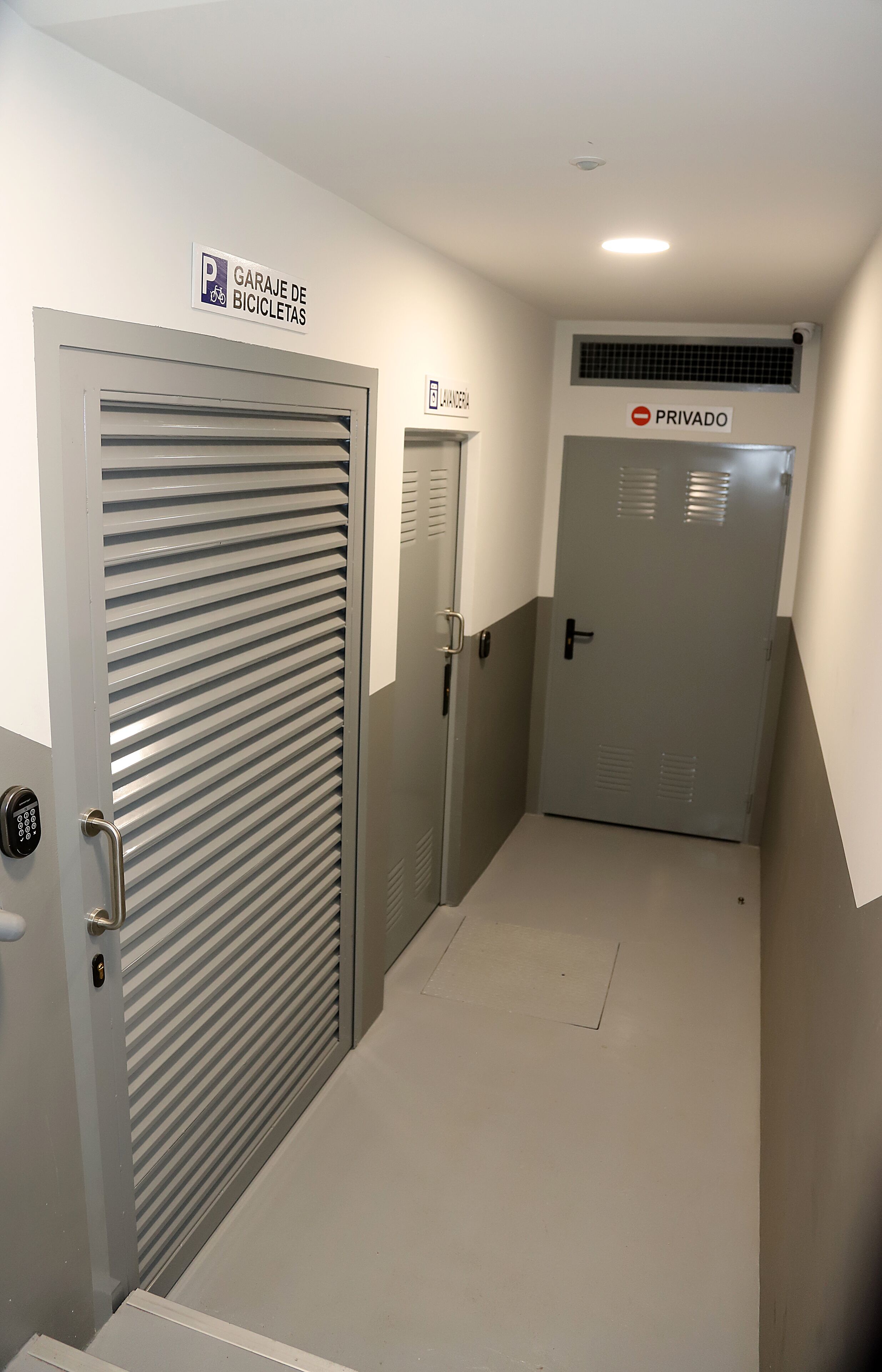 Un pasillo con zona de estacionamiento para bicicletas, puerta privada y puerta de seguridad.