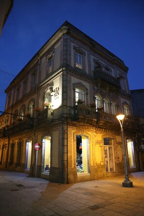 A historic building with a prominent entrance, large windows, and a balcony with flowers. - Vía XIX (Caldas de Reis)