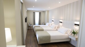Una habitación de hotel con tres camas, un escritorio y una silla.