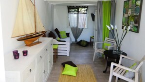 Un salon chaleureux avec une maquette de voilier, un canapé, des fauteuils et une table à manger.