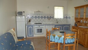 Cocina compacta con comedor, microondas, estufa y fregadero.