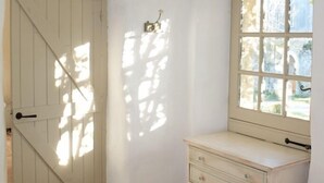 Una stanza con una porta bianca, una finestra con vista e una piccola scrivania.
