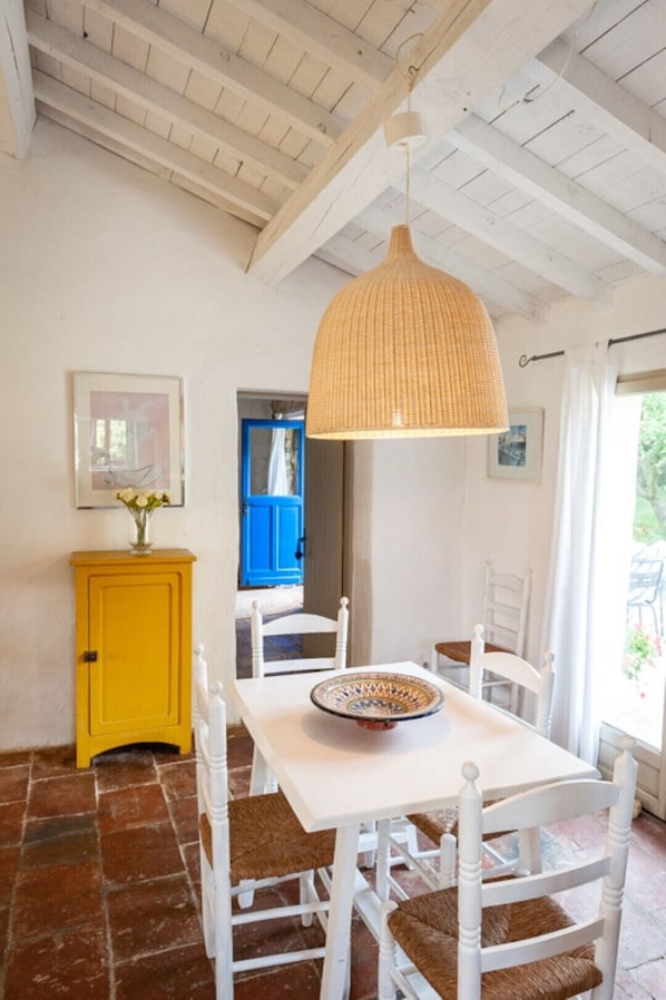A dining area with a white table and chairs, a yellow cabinet, and a hanging light fixture. - A pretty cottage in the middle of a park in the south-west countryside (Pech-Luna)