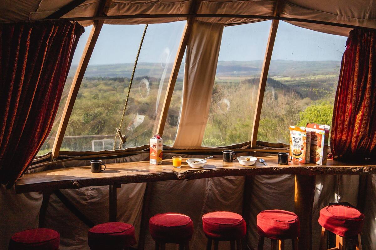 A cozy interior with a bar area, stools, and a view of the landscape through large windows.