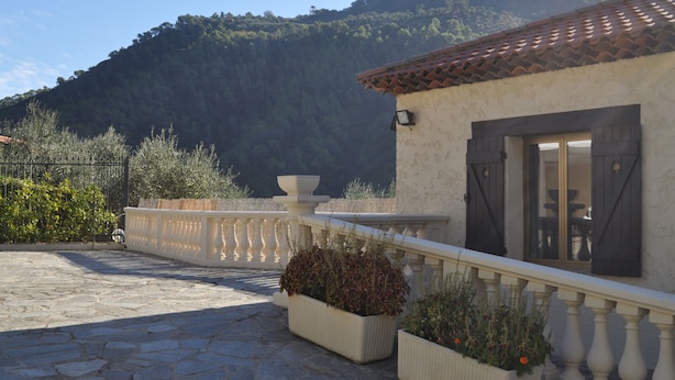 A stone-paved patio with a white balustrade, potted plants, and a view of a mountain. - Beautiful holiday villa overlooking the sea and the mountains (Dolceacqua)