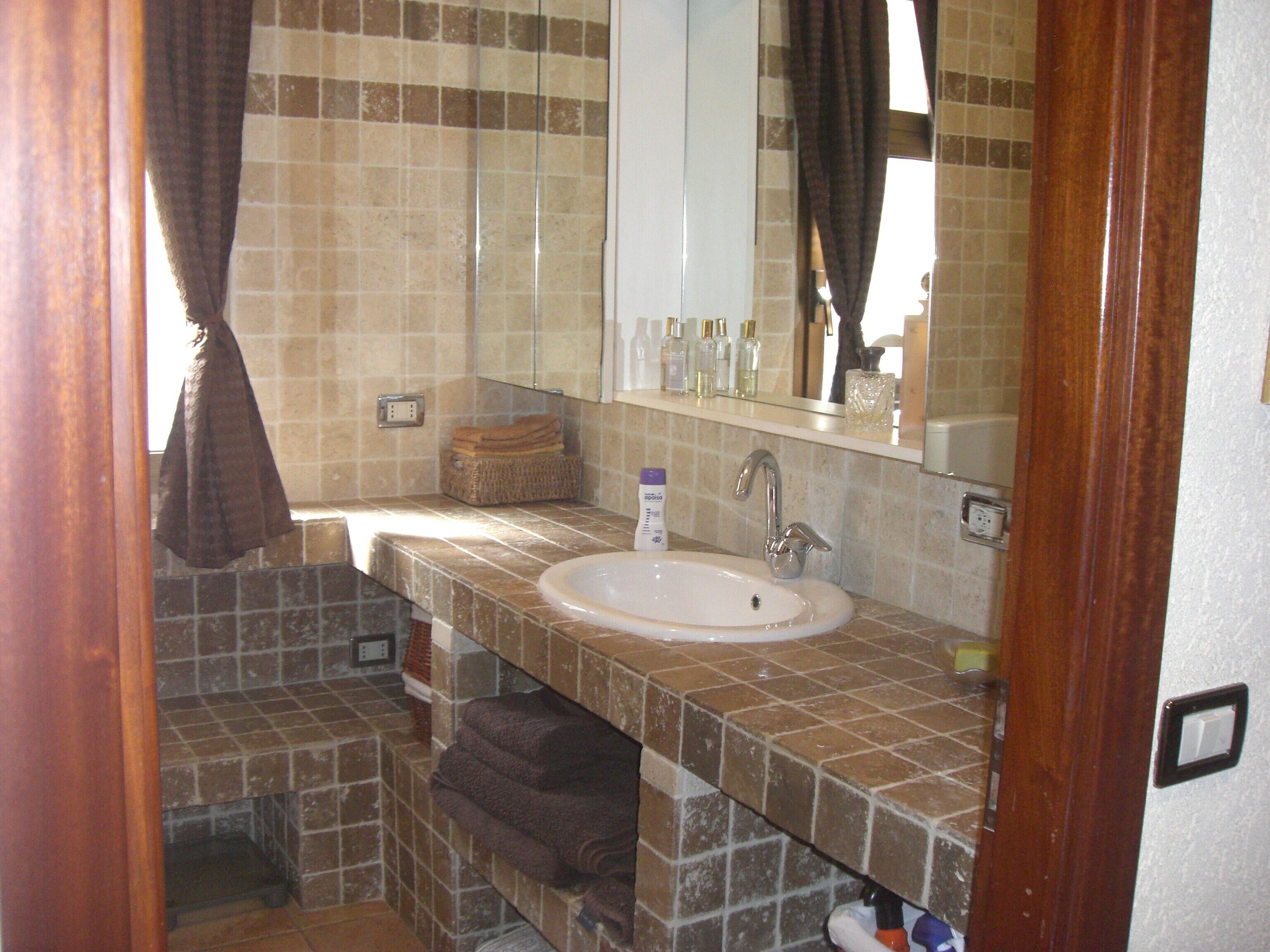 A bathroom with a sink, mirror, and tiled walls.