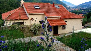 A traditional house with a red-tiled roof, a small balcony, and a garden with blue flowers. - Beautiful holiday villa overlooking the sea and the mountains (Dolceacqua)