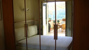 A bedroom with a bed, a wardrobe, and a view of an outdoor patio area. - Beautiful holiday villa overlooking the sea and the mountains (Dolceacqua)