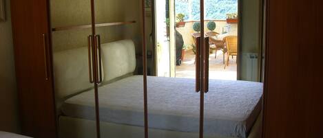 Quarto com cama, guarda-roupa e vista para um pátio.