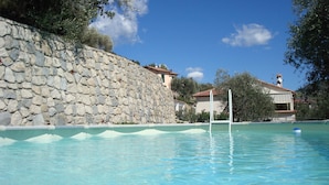 A swimming pool with a stone wall and a clear blue sky. - Beautiful holiday villa overlooking the sea and the mountains (Dolceacqua)