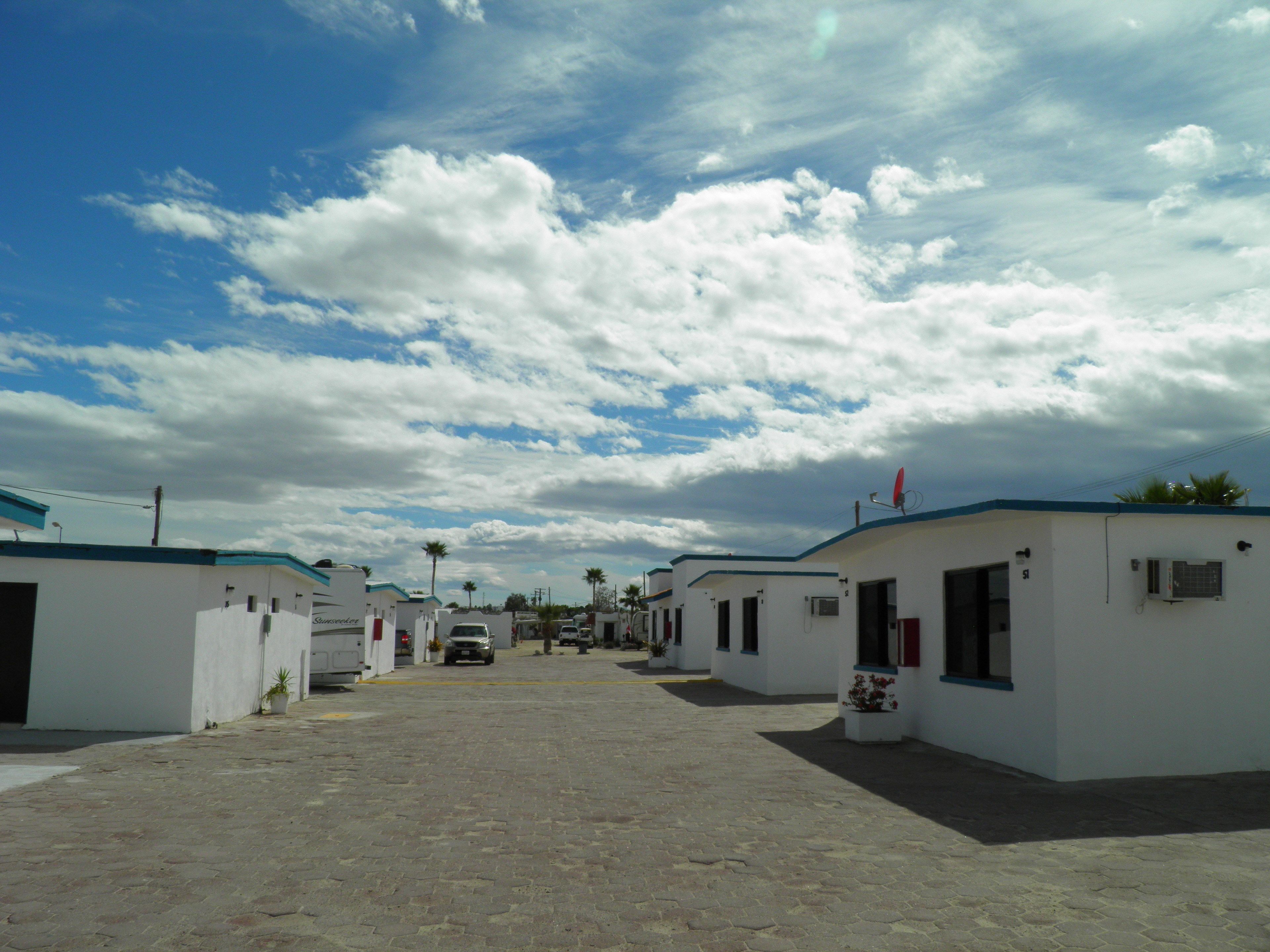 A row of small, white buildings with blue roofs, arranged in a linear fashion.